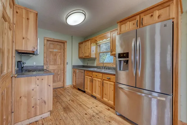 a kitchen with granite countertop a refrigerator stove top oven and sink