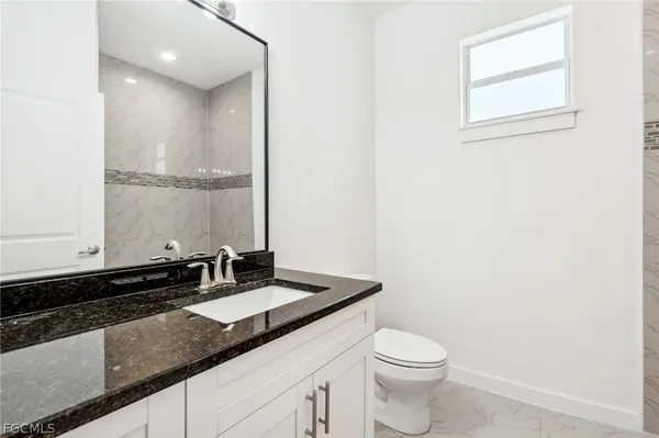a bathroom with a granite countertop sink a toilet and a mirror