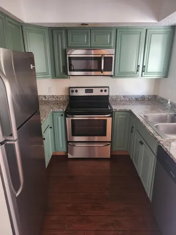 a kitchen with granite countertop a refrigerator stove and microwave