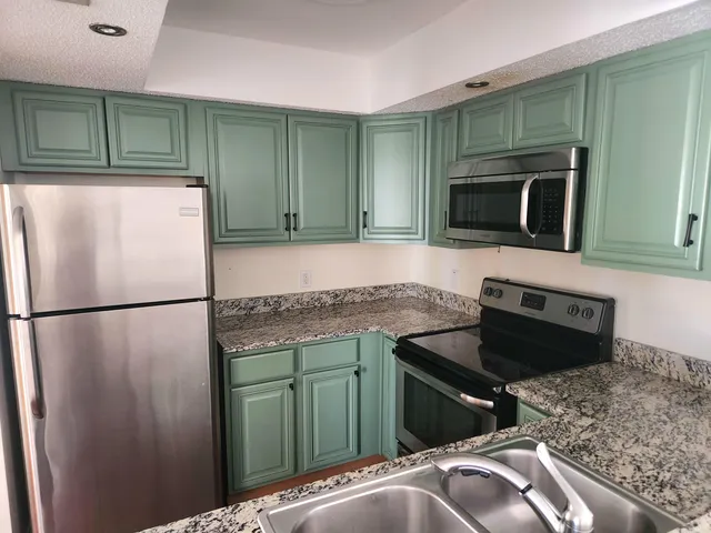 a kitchen with granite countertop a refrigerator and a microwave