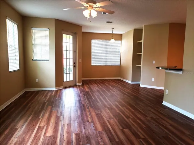 an empty room with wooden floor and windows