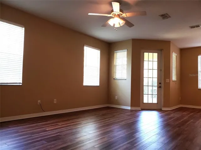 a view of an empty room with wooden floor and a window