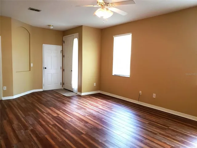 an empty room with wooden floor and windows