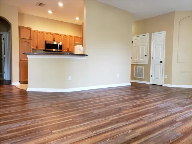 a view of a kitchen with stainless steel appliances wooden floor and chair