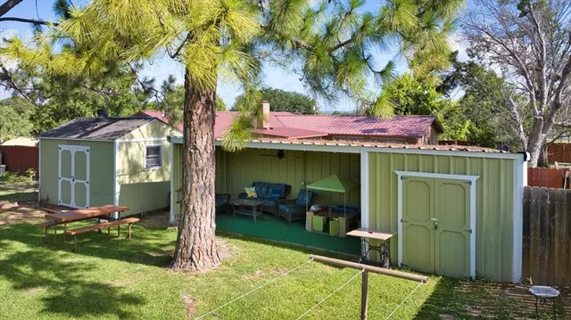 a view of a backyard with table and chairs and a large tree