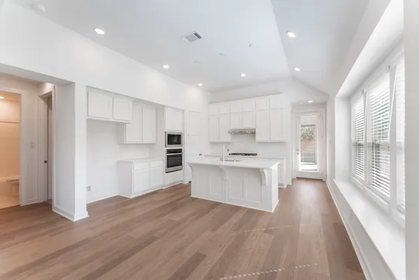 a kitchen with white cabinets and wooden floor