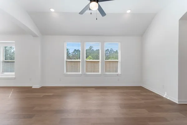 an empty room with wooden floor and windows