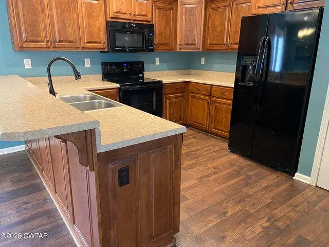 a kitchen with stainless steel appliances granite countertop a refrigerator a stove top oven a sink and dishwasher