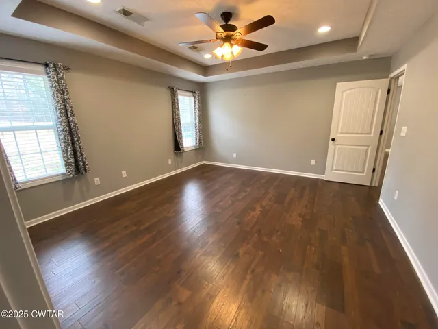 a view of an empty room with window and wooden floor