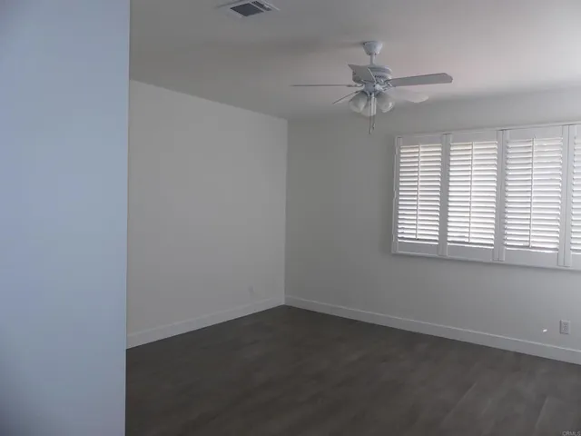 an empty room with windows and fan