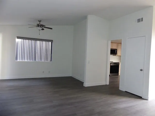 an empty room with wooden floor chandelier and windows