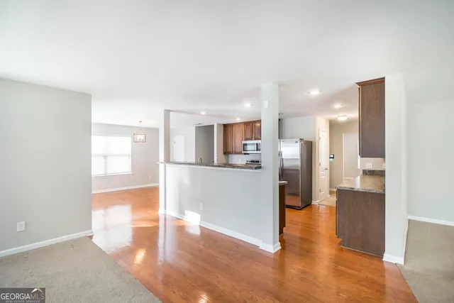 a view of kitchen with refrigerator stove and wooden floor