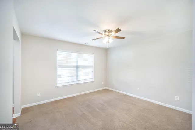 an empty room with a window and a ceiling fan