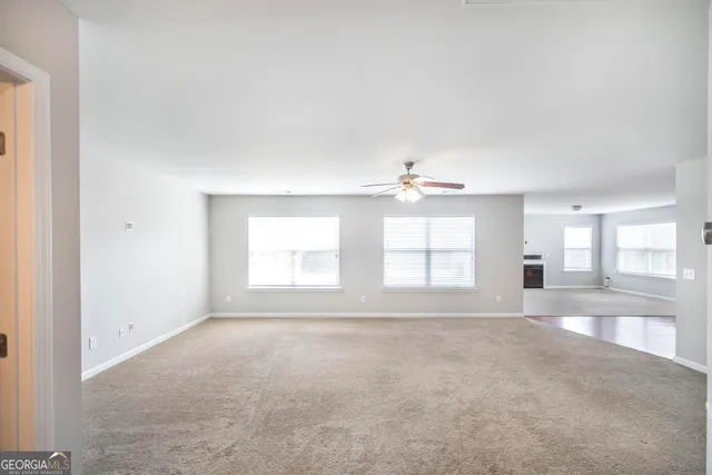 an empty room with windows and chandelier fan
