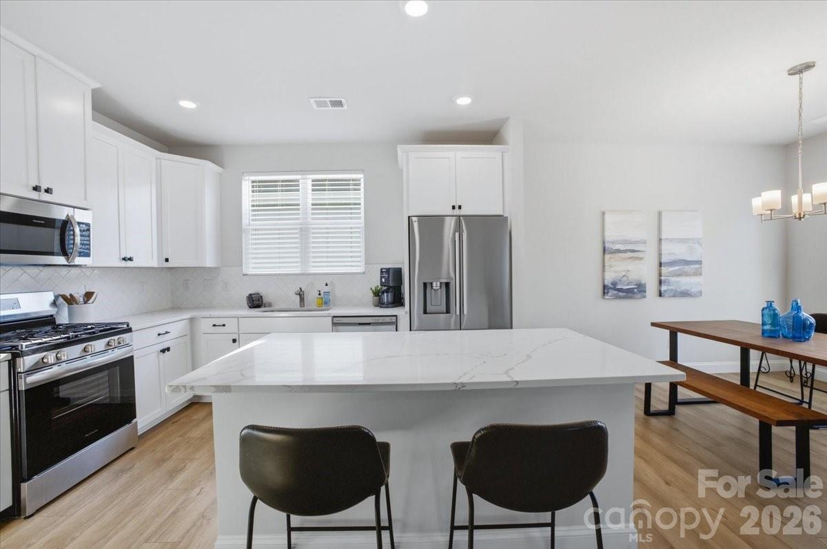 602 Banter Lane Cramerton, NC 28056 - Photo 5 of 33 a kitchen with stainless steel appliances granite countertop a dining table chairs stove refrigerator and cabinets
