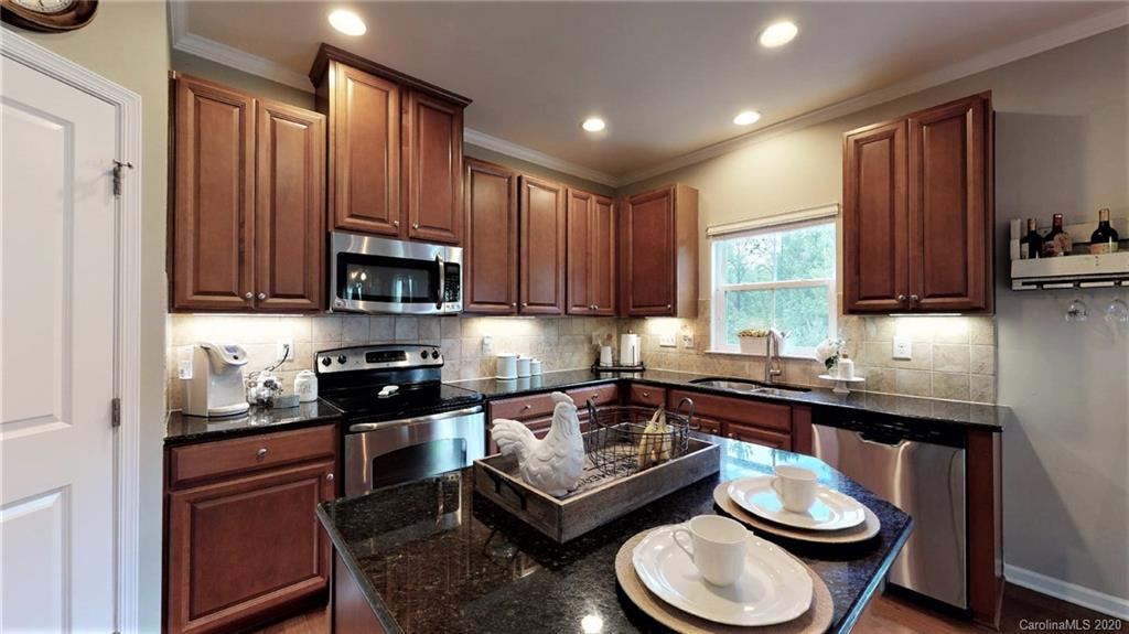 3010 Fallondale Road Waxhaw, NC 28173 - Photo 18 of 44 a kitchen with a sink a stove a microwave and wooden cabinets