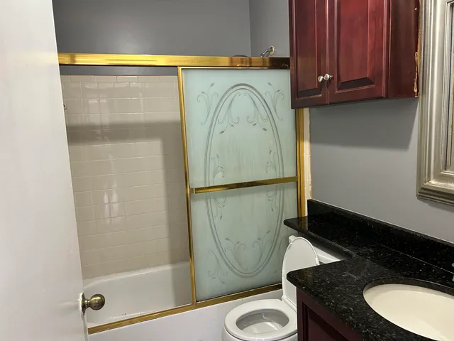 a bathroom with a granite countertop sink a toilet and a mirror