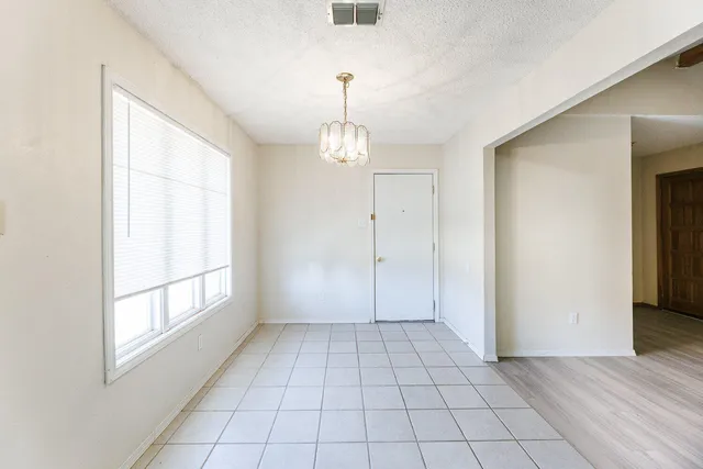 a view of an empty room with window and chandelier fan
