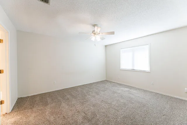 an empty room with windows and fan