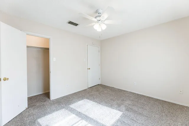 an empty room with windows and ceiling fan