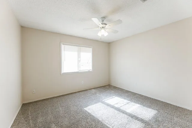 an empty room with a window and a fan