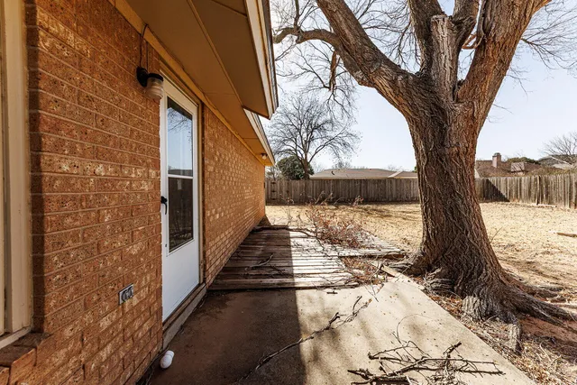 a view of a yard with wooden fence and a large tree