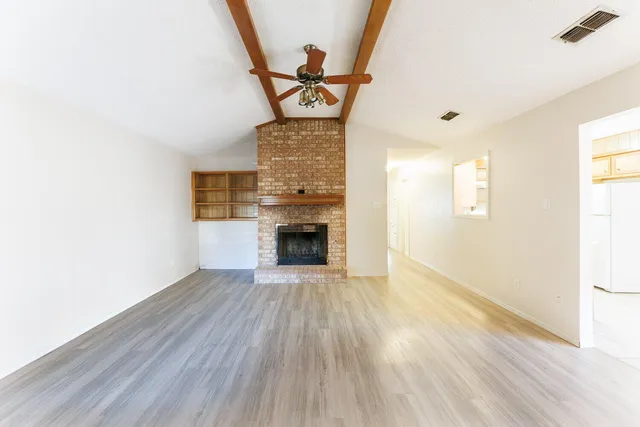a view of a livingroom with wooden floor a fireplace and windows