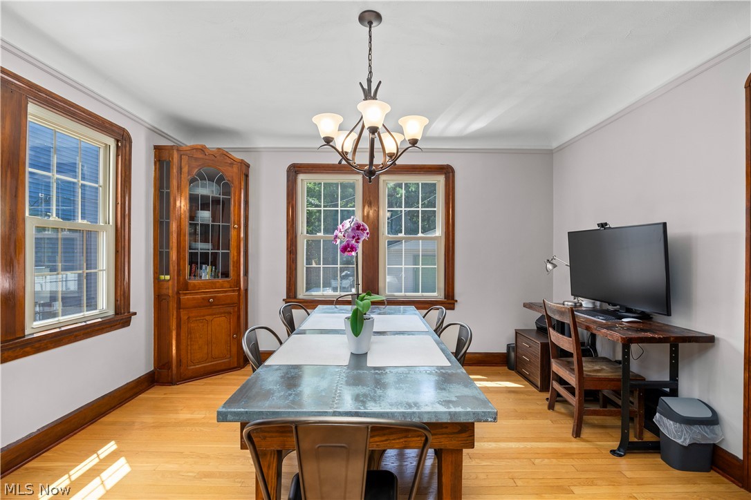 26019 Lake Road Bay Village, OH 44140 - Photo 18 of 40 Spacious dining area featuring warm wood-finish flooring, multiple windows with natural wood trim, a built-in corner display cabinet, a central chandelier, and crown molding