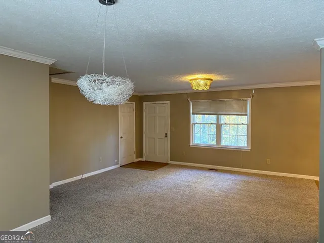 a view of an empty room with window and chandelier fan