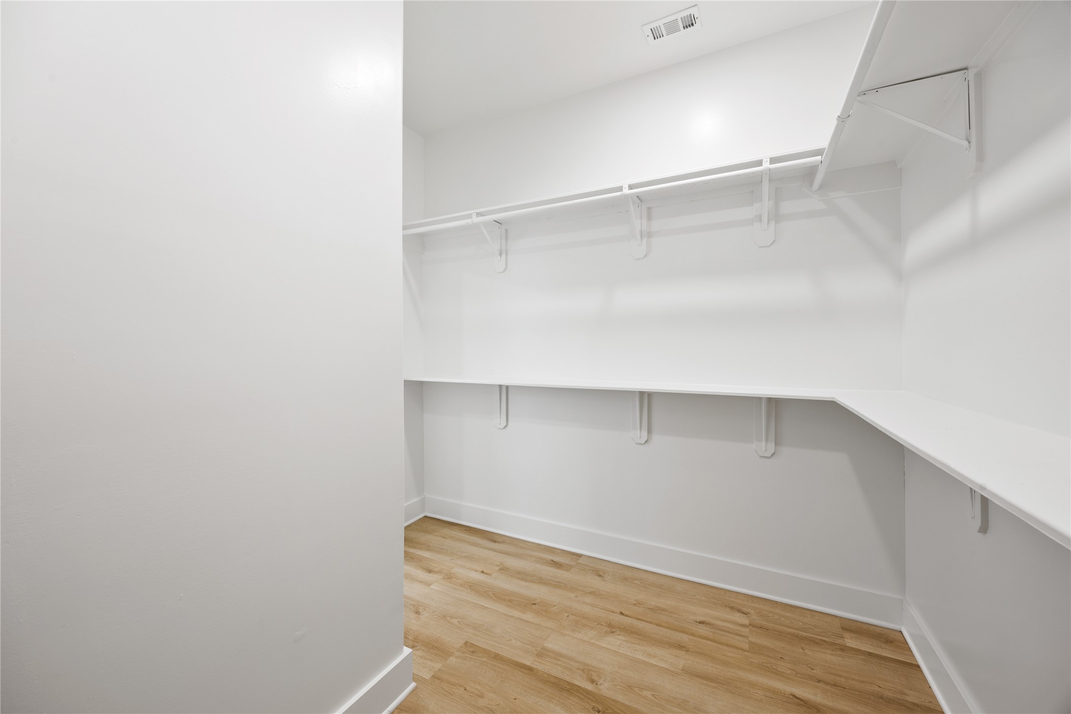 1121 Austin Street Rosenberg, TX 77471 - Photo 33 of 44 This is a spacious walk-in closet with white walls, ample shelving, and hanging space. It has a light luxury vinyl floor, providing a clean and organized look.
