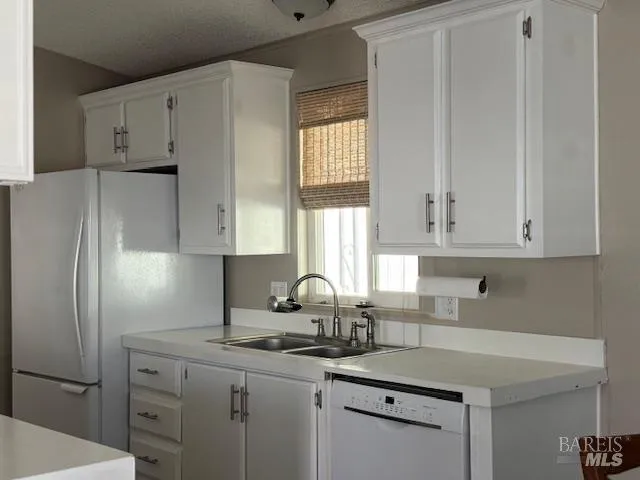 a kitchen with white cabinets and a refrigerator