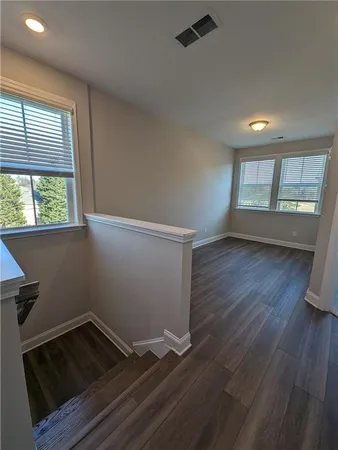 an empty room with wooden floor and windows
