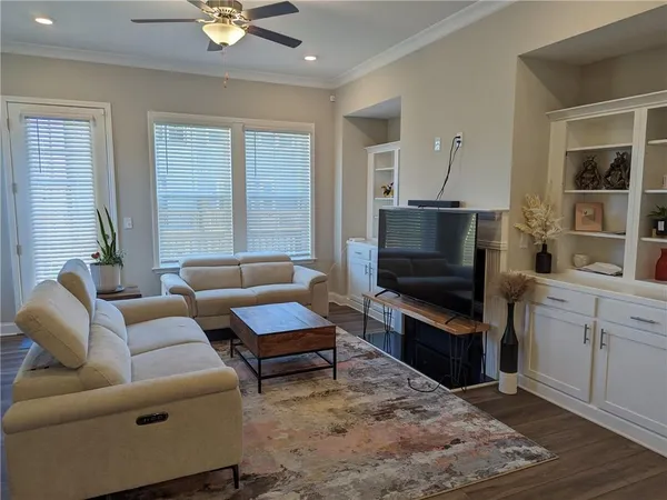 a living room with furniture a ceiling fan and a flat screen tv