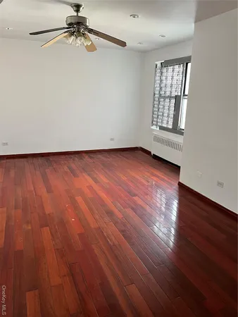 an empty room with wooden floor fan and windows