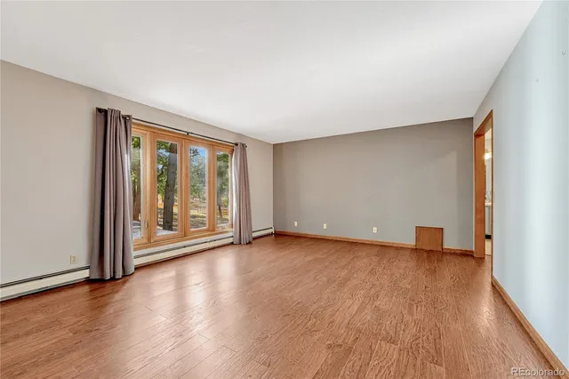 a view of an empty room with glass door and wooden floor
