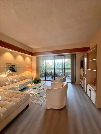 a living room with couches and kitchen view with wooden floor