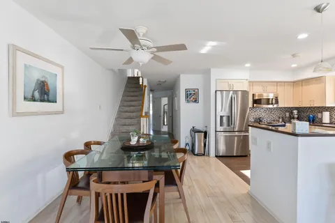 a kitchen with stainless steel appliances kitchen island granite countertop a dining table chairs refrigerator and sink