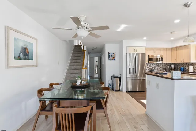 a kitchen with stainless steel appliances kitchen island granite countertop a dining table chairs refrigerator and sink