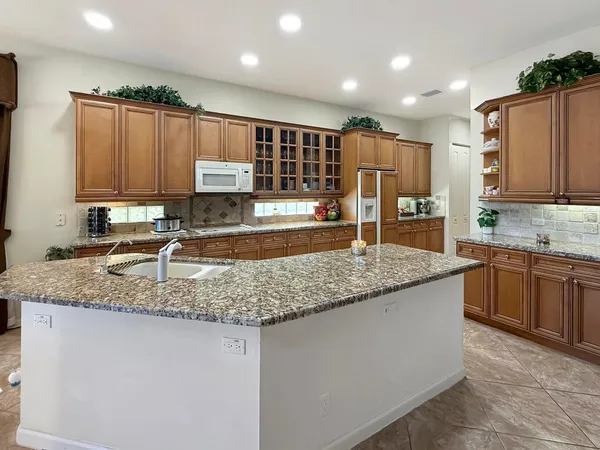a kitchen with kitchen island granite countertop a sink a counter top space appliances and cabinets