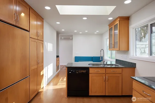 a kitchen with kitchen island granite countertop a sink and wooden cabinets