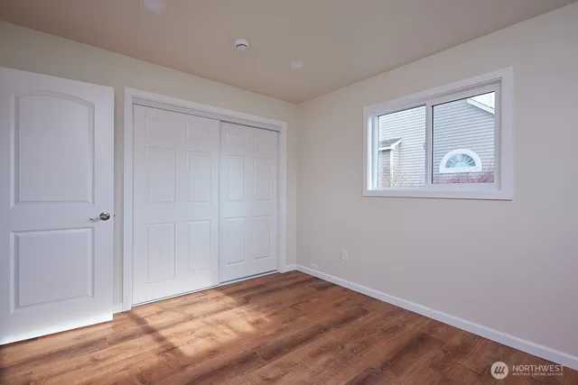 a view of an empty room with wooden floor and closet