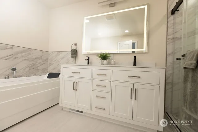 a bathroom with a sink a vanity a mirror and bathtub
