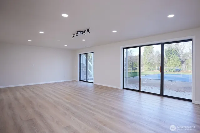 an empty room with wooden floor and windows with balcony view