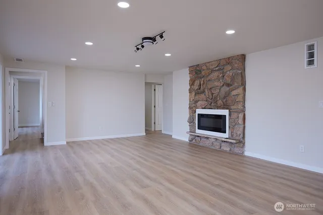 a view of an empty room with wooden floor a fireplace and a window