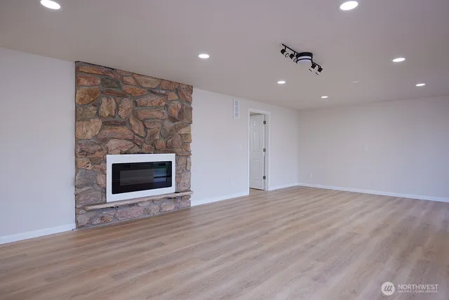a view of an empty room with wooden floor and a fireplace