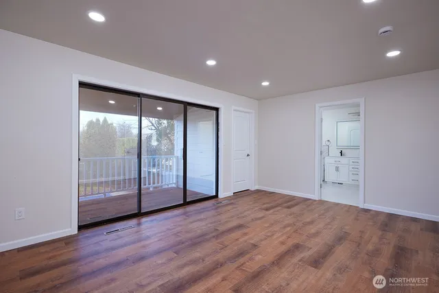 a view of an empty room with wooden floor and sliding door