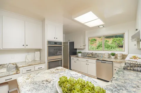 a kitchen with kitchen island granite countertop white cabinets and stainless steel appliances