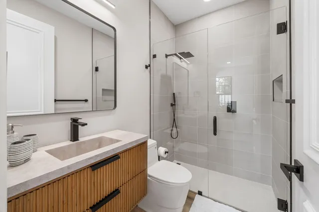 a bathroom with a double vanity sink toilet mirror and shower