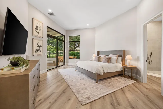 a spacious bedroom with a bed and a flat screen tv