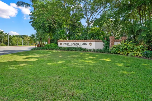 a sign that is sitting in the grass near a tree